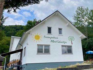 Das weiße Hauptgebäude des Ferienzentrums Albert Schweitzer in Vöhl mit bunten Malereien an der Fassade.