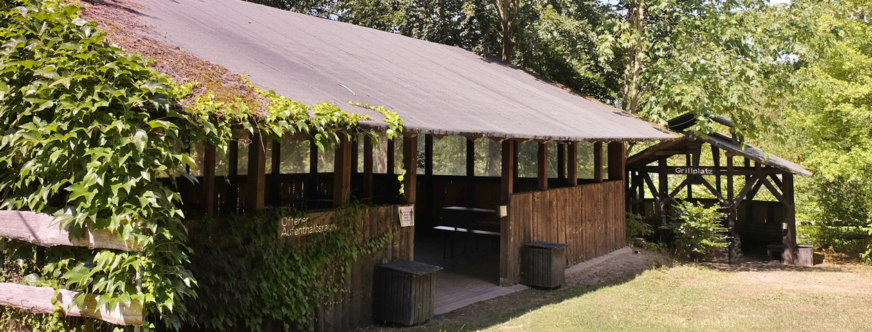 Ein überdachter Aufenthaltsraum aus Holz neben einem Grillplatz im Ferienzentrum Albert Schweitzer in Vöhl.